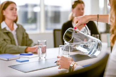 Woman in a meeting pouring a glass of water